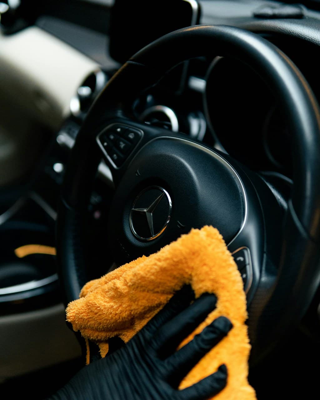 Detailer wiping down a luxury car interior